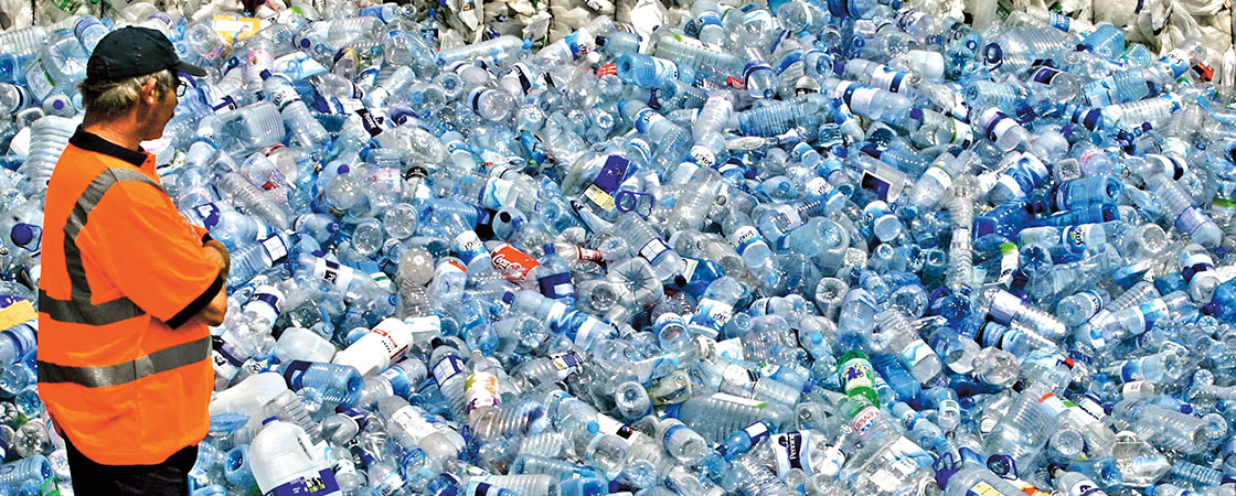 a man looking at a large pile of empty plastic bottles