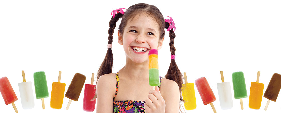 a girl with pigtails smiling while holding an ice pop with a row of ice pops behind her