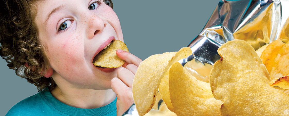 a boy eating from a bag of potato chips
