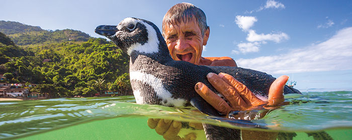a man holding a penguin in the water 