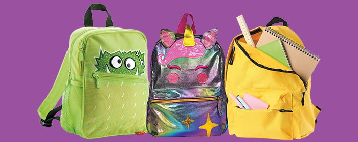 Three colorful children's backpacks: a green monster, a unicorn, and a yellow pack filled with school supplies